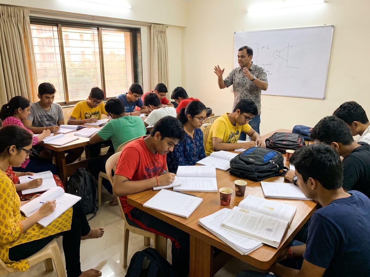 Teenagers taking notes in a coaching class while a teacher explains